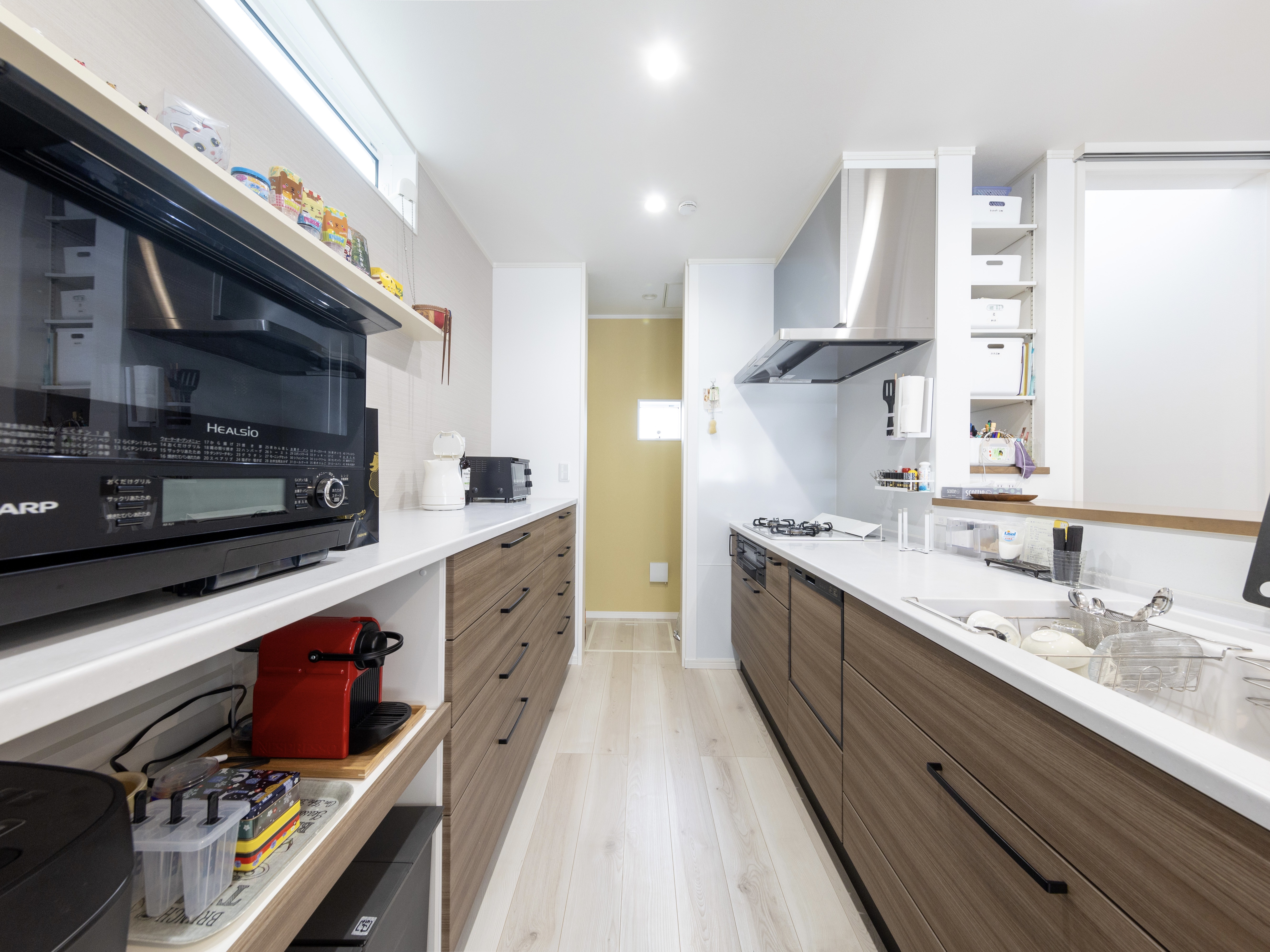 エスホーム｜シンプルでモダンなデザインのキッチン。広々とした作業スペースと収納が充実しており、効率的な料理をサポートしている。飲み物は各自で取れるように、冷蔵庫をダイニング側に置いた。