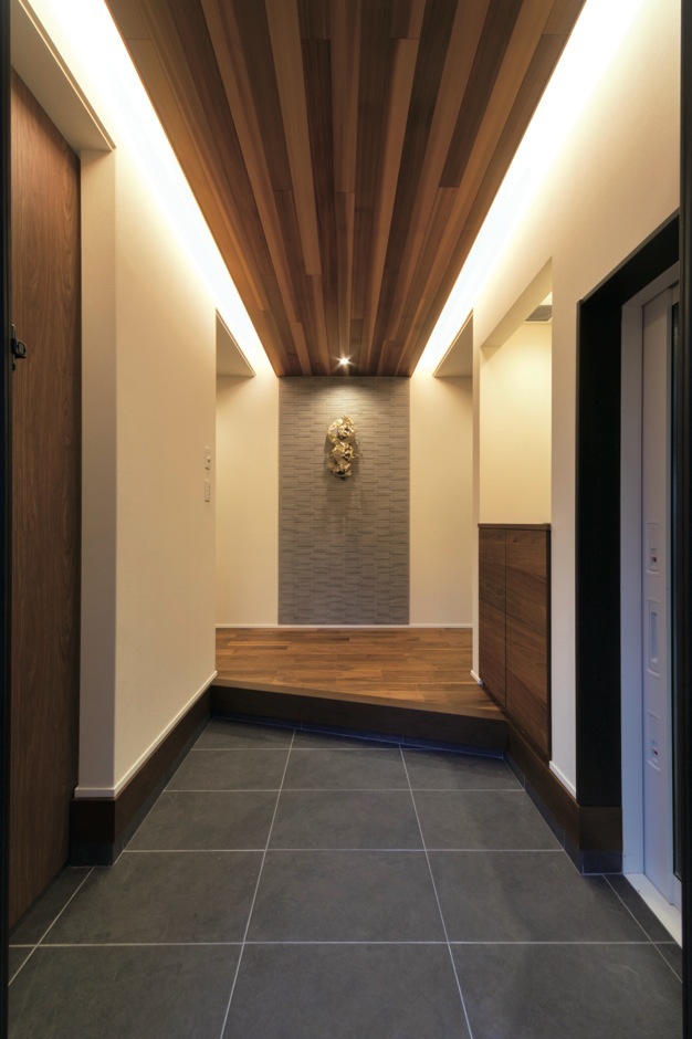 インナーガレージから直結の玄関ホール。天井の一部にレッドシダーを貼りアクセントを。正面のタイルは調湿・消臭効果の高いエコカラットを採用した