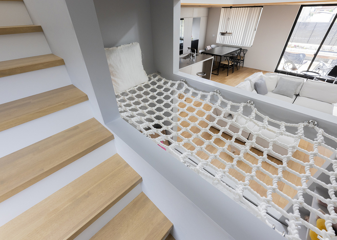 階段の脇には「DEN」の天井にはネットがあり、子どもが階段からネットに飛び乗って浮遊感を楽しめる。ユニークなアイデアが子どもにも大好評。壁を設けずオープンにしたことで、空間に抜け感や開放感も確保できた