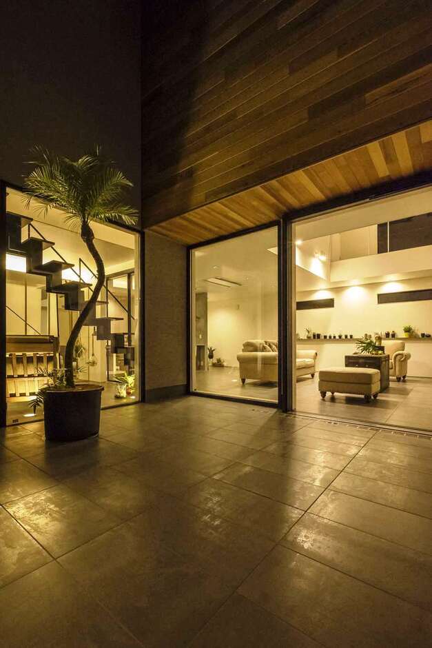 家の一部として取り込まれたプライベート感満載の中庭。リビングと同じタイルを敷き、一体感を演出している。軒や壁の無垢材、塗り壁との対比も絶妙