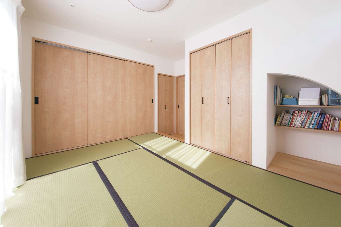 コットンハウス【子育て、省エネ、間取り】主寝室には自由度の高い和室を選択。布団を片づけることで多目的に使うことができる。掃き出し窓に続くテラスに洗濯物を干し、取り込んで収納するまですべてこの部屋で完結する。収納の取っ手は統一感をもたせるために黒く塗装してもらった