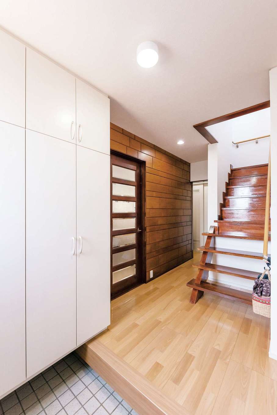興友ハウス｜リノベーション前からあった木の壁をそのまま残 えたした玄関ホール。階段の左側にそびえ立つようについていた手すりを取り外し、窮屈さを緩和した