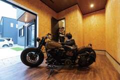 6畳のインナーバイクガレージ。壁はOSB合板、床はフロアタイルを貼って、ワイルドな雰囲気を演出。ソファやテレビ、工具棚を設置して、愛車のハーレーをいじったり、一人の時間を楽しんだり。ガレージの中から玄関へは直接アクセスできる