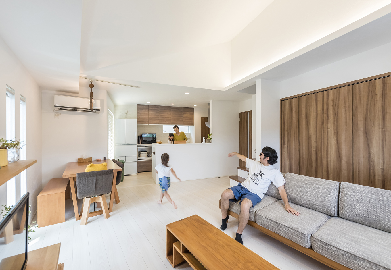 住起産業（アキュラホーム三島中店）【二世帯住宅、狭小住宅、屋上バルコニー】リビング・ダイニングが見渡せるキッチンは、お子さんがお手伝いしやすいのもポイント。キッチンの横には小さなバルコニーがあり、プランターを置いて小さな家庭菜園も楽しめる。勾配天井や間接照明が、空間に広がりをもたらす