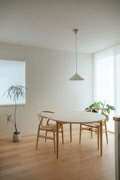ナチュラルテイストの空間に合うようにセレクトしたシンプルな丸型のダイニングテーブルとYチェア。照明、グリーンとの相性もぴったりで、素材感を楽しむことができる。フローリングは床暖房仕様。大開口を開けると四季折々の中庭の景色が広がる