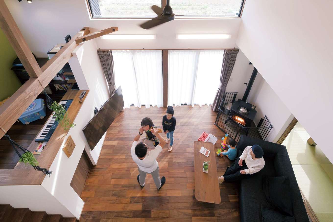 神谷綜合建設 カミヤの家【収納力、間取り、スキップフロア】高い断熱性、バランスのいい建具の配置、シーリングファンのおかげで、効率よく冷暖房を活用できている。写真は、2階ホール部分の窓を開け、吹き抜け越しにリビングを見下ろしたところ
