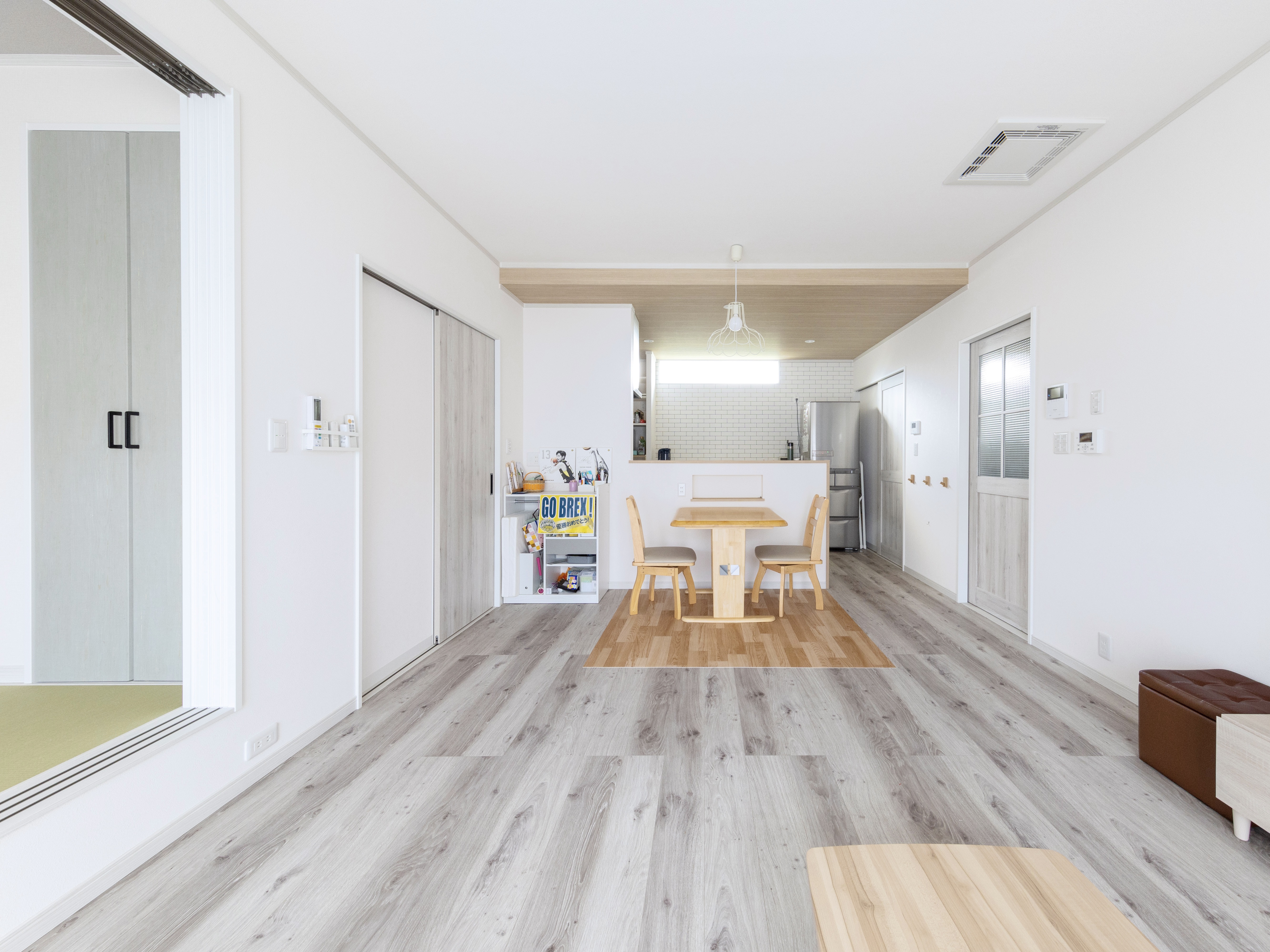 エスホーム｜広々としたLDKは、シンプルでモダンなデザインが特徴。白を基調とした爽やかな空間に木目の暖かさが加わり、家族が集う心地よい場を作り出している。