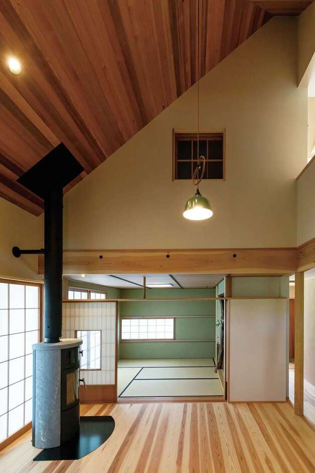 吹抜けのダイニングに北欧製の薪ストーブを設置。床と天井は天竜杉。リビング兼茶室は旧家の建具の高さに合わせて設計した