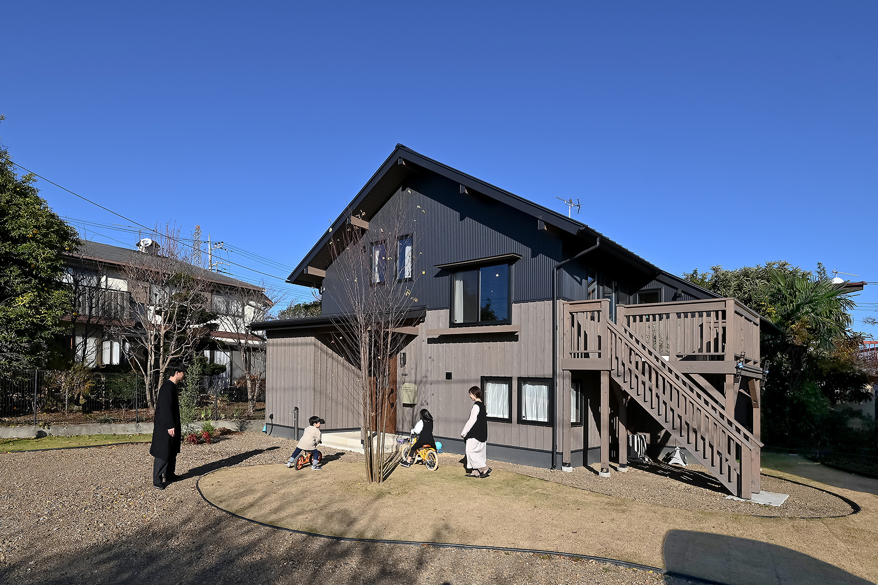 ネクストハウスデザイン｜庭付きの広々とした一戸建て住宅の外観。木製のバルコニーとシンプルなデザインが魅力で、自然と調和した佇まい。