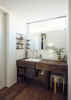 オリジナルの洗面化粧台も濃い木目で統一。2人で並んで朝の支度ができるように、カウンターを広くし、スペースにもゆとりを持たせてある。メイクやスキンケアを座ってゆっくりできるように、椅子をおけるスペースも確保した