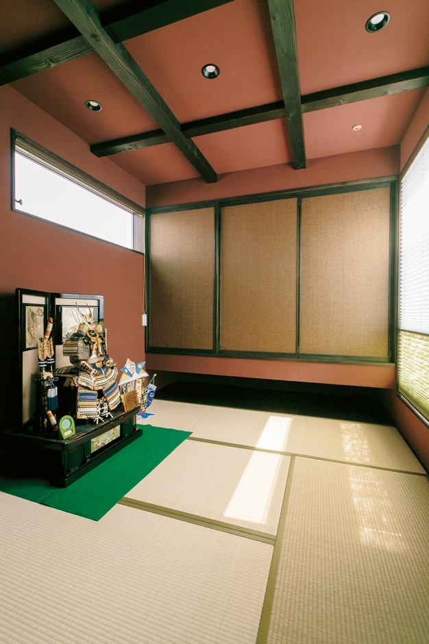 梁を現しにしてあえて天井を高くした和室。小豆色の塗り壁は調湿・消臭効果に優れた100％自然素材の薩摩中霧島壁