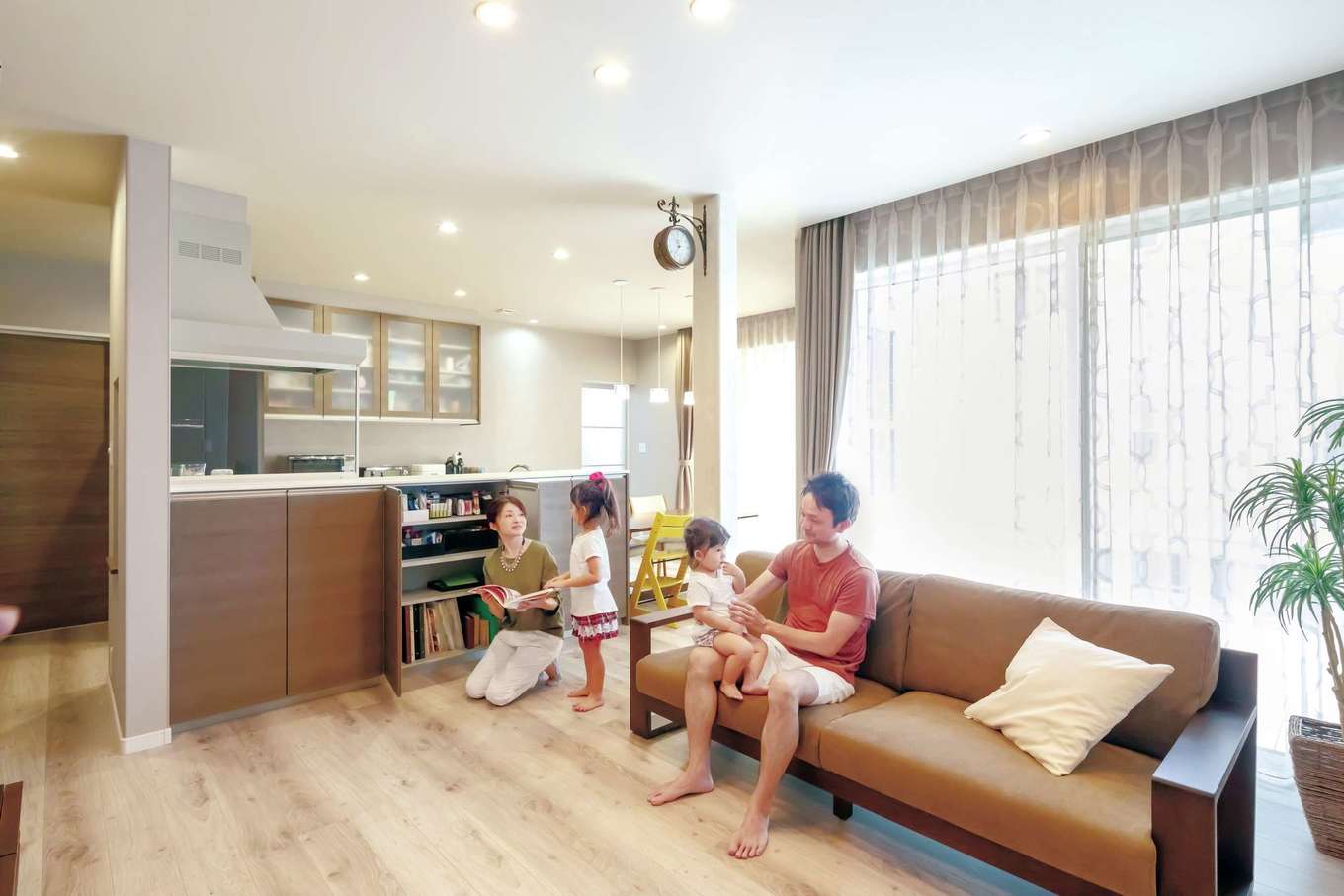 遠州鉄道 遠鉄ホーム【子育て、収納力、間取り】南面に大開口を設けた明るいLDK。フローリングの色と質感に合わせて、クロスは淡いグレーを採用。キッチンを中心にぐるぐると回遊できる間取りが共働き・子育てママの家事負担を軽減する