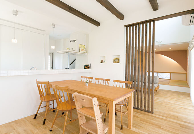 リビングとダイニングは格子の仕切りでやわらかく分離。開放感と一体感を保ちつつ、穏やかに役割を分け、それぞれの場所における団らんを落ち着いたものに。キッチン背面の食器棚は中身を隠せるようにしてもらった