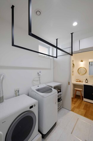 明るく使いやすい洗面スペースとランドリールームが一体化した空間。大型の洗濯機と乾燥機が配置されており、室内干しが可能な設計が便利である。