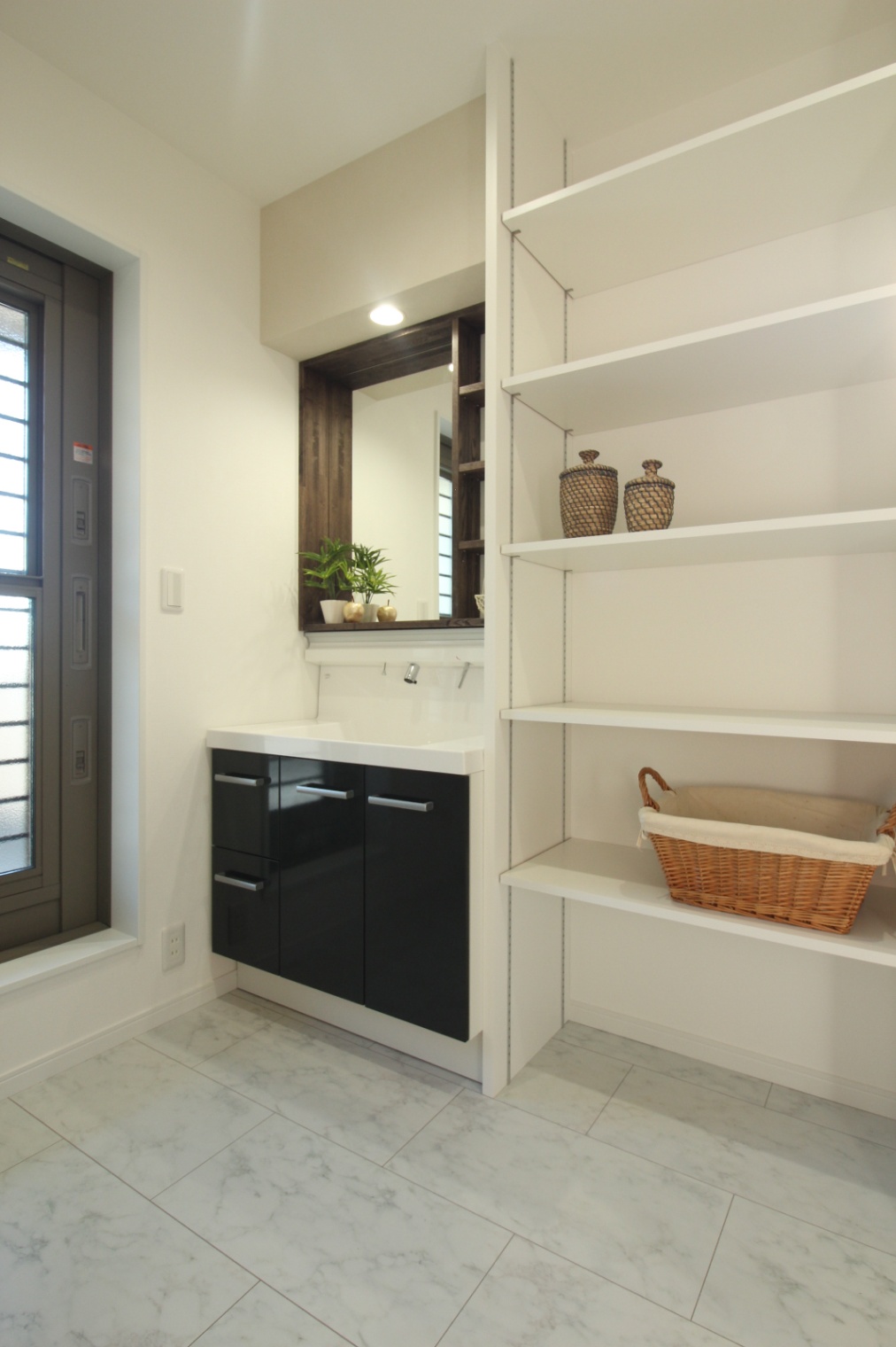 小野田産業～designers house project～｜明るく洗練された洗面スペース。窓から自然光が差し込み、収納棚にはタオルや小物を整理して収められるようになっている。