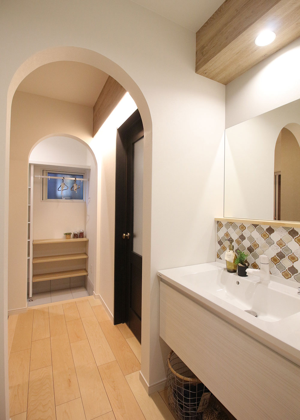小野田産業～designers house project～【1000万円台、デザイン住宅、子育て】玄関からは左側にシューズクローク、右側に洗面や浴室などの水回りがある。入口のアーチ曲線が、玄関ホールをやわらかな雰囲気で包んでくれる