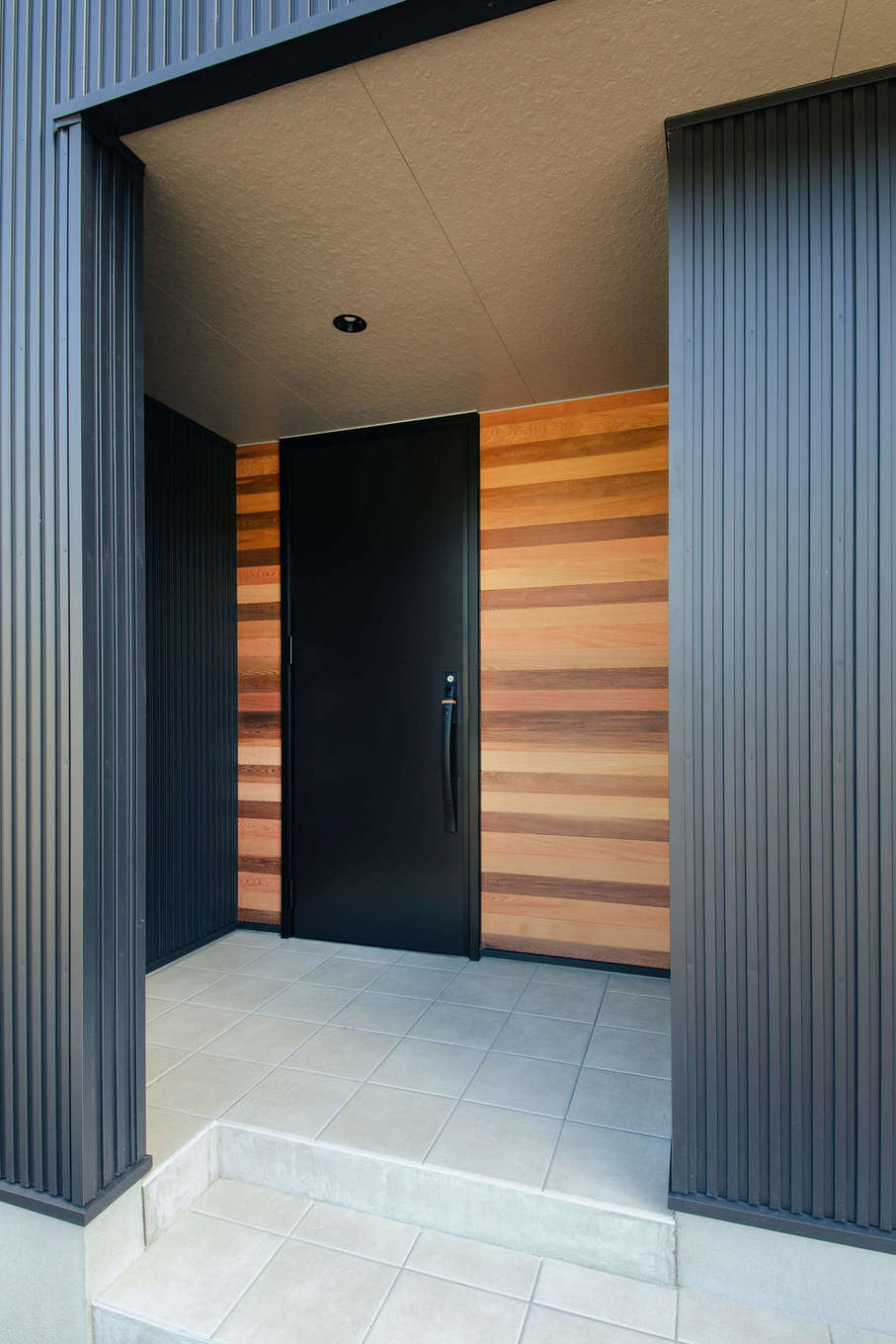 DAITOKU（大得工務店）【デザイン住宅、省エネ、間取り】玄関ドアの回りに無垢のレッドシダーを採用し、外観のアクセントに。ガルバリウム鋼板の外壁と木の温もりがバランスよく調和している