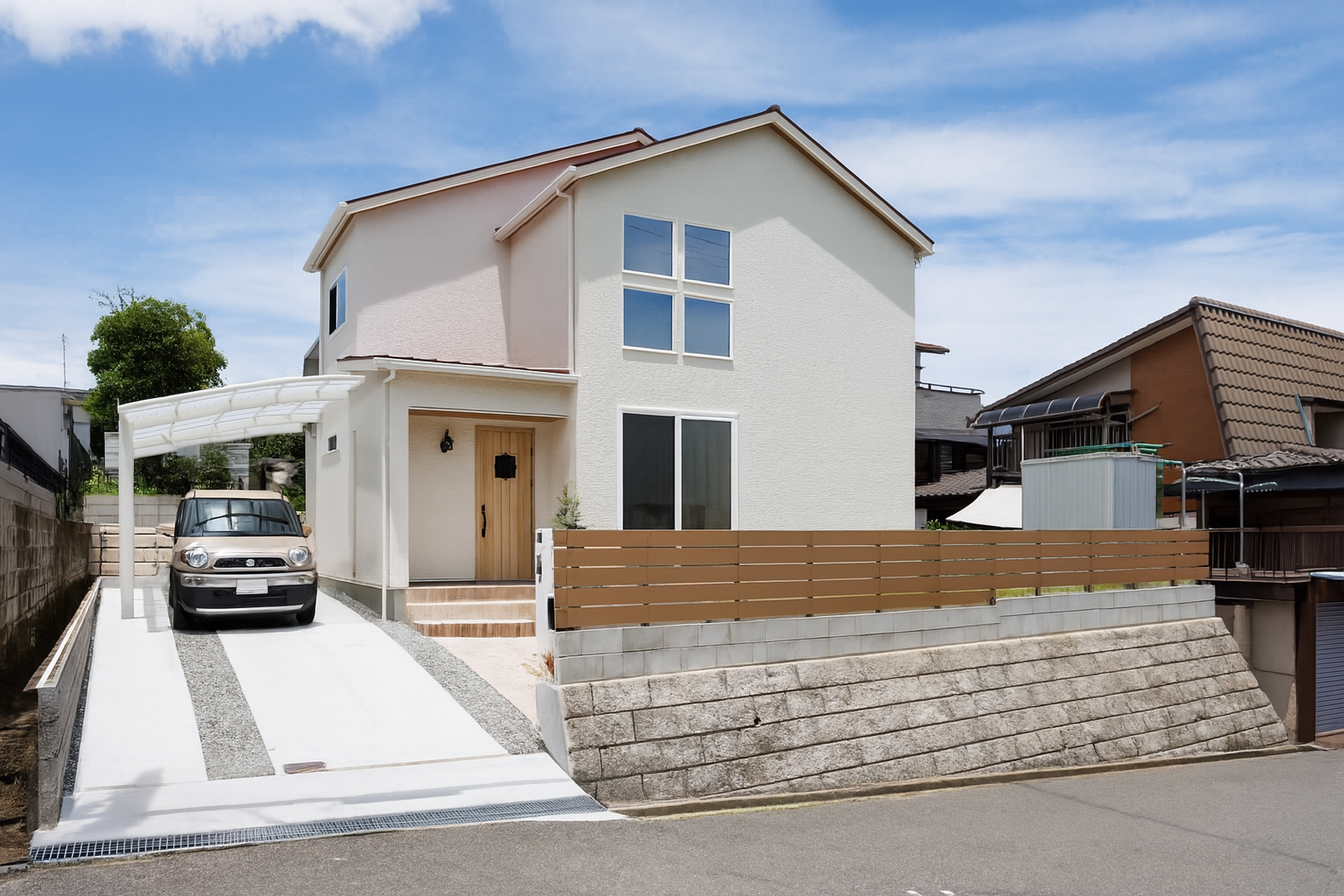 アーキホームライフ｜青空の下に立つモダンな二階建て住宅の外観。シンプルなデザインと、白を基調とした外壁が清潔感を演出している。車が停められたカーポートも完備。