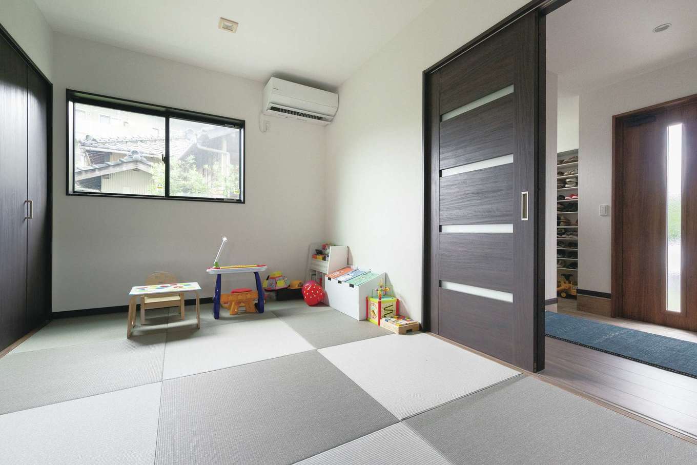三和建設【デザイン住宅、子育て、間取り】玄関からも直接出入りできる和室。モダンなグレーのコントラストの琉球畳を採用。客間やご主人のひと休みスペースの他、小上がりの畳コーナーと併せて子どもの遊び場やお昼寝スペースにも活躍している