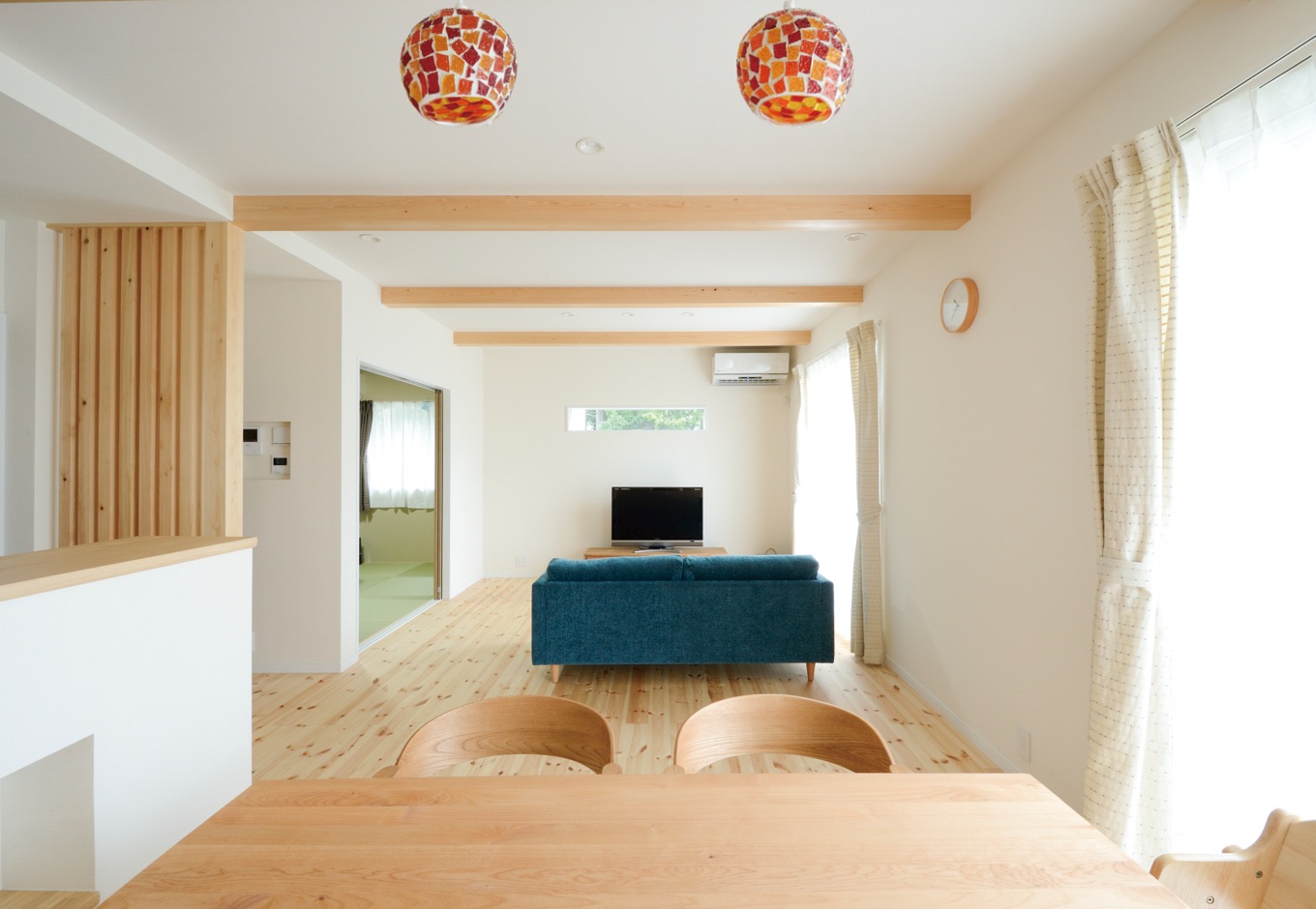 内田建設【収納力、間取り、建築家】20畳のLDK。南面の大きな開口部を開けると、ウッドデッキを介して庭とつながる。TVの上のスリット窓からも緑の借景を楽しめる