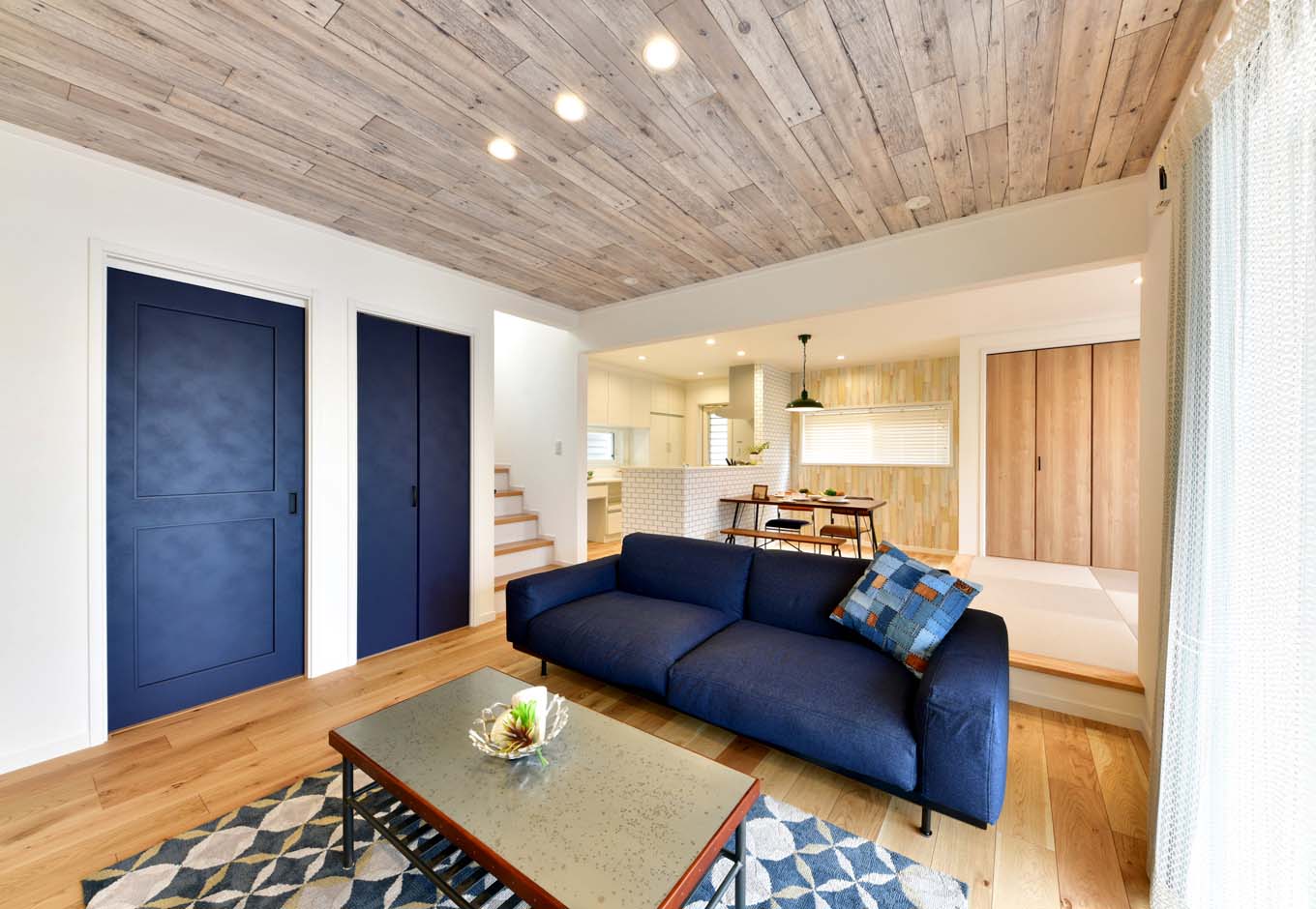 静鉄ホームズ【デザイン住宅、趣味、インテリア】ヴィンテージ加工されたブルーの建具がポイントとなり、木のぬくもりを感じるリビング空間。天井で使用している古木調のクロスも海岸沿いの暮らしをイメージしている。