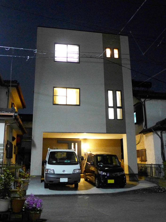 建築システム（狭小住宅専門店）【二世帯住宅、ペット、ガレージ】夜の外観。トラックがあるということは水道工事のお仕事をされているお父さんが帰宅されたという事