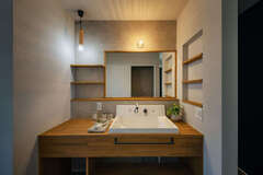 職人手づくりの洗面台と鏡。施主さん支給のおしゃれな照明が木のぬくもりに満ちた空間にベストマッチ