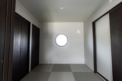 シンプルでモダンな和室空間。円窓が特徴的で、静かな時間を感じさせる落ち着いた雰囲気が漂う。収納スペースも充実。