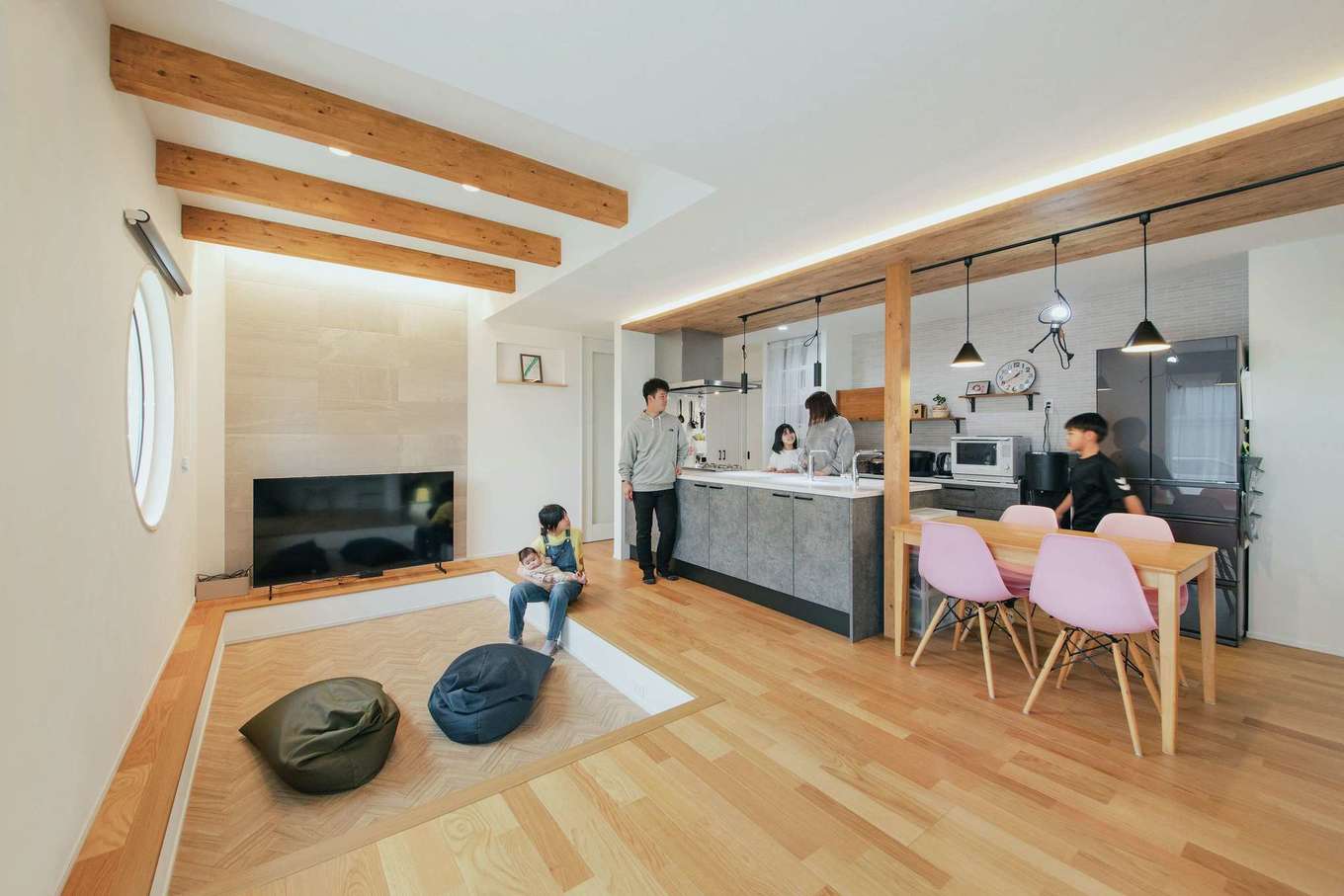 子育て安心住宅 Design Craft Office【デザイン住宅、収納力、間取り】ダウンフロアのリビングとアイランドキッチンを採用し、家族６人がゆったりくつろげる空間をデザインしたLDK。キッチンの下がり天井やリビングの天井の化粧梁など、木をアクセントに活かしている