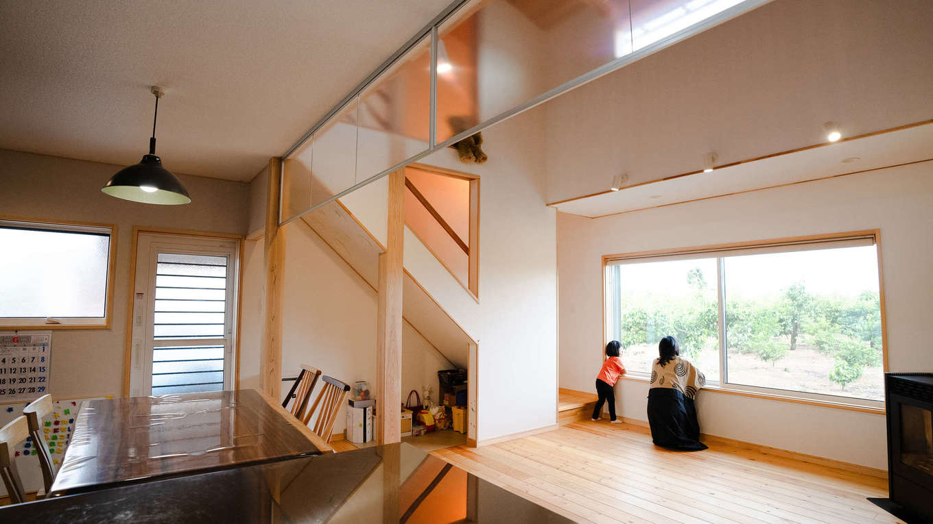 瀧口建設【和風、自然素材、平屋】大きな窓と吹き抜けのある開放的な空間に、無垢アカマツの床、珪藻土クロス、木製家具がぬくもりをもたらすLDK。子どもと一緒に景色を眺める時間も宝物。「光が届き、風がよく通るので快適に過ごせています」と話す奥さま