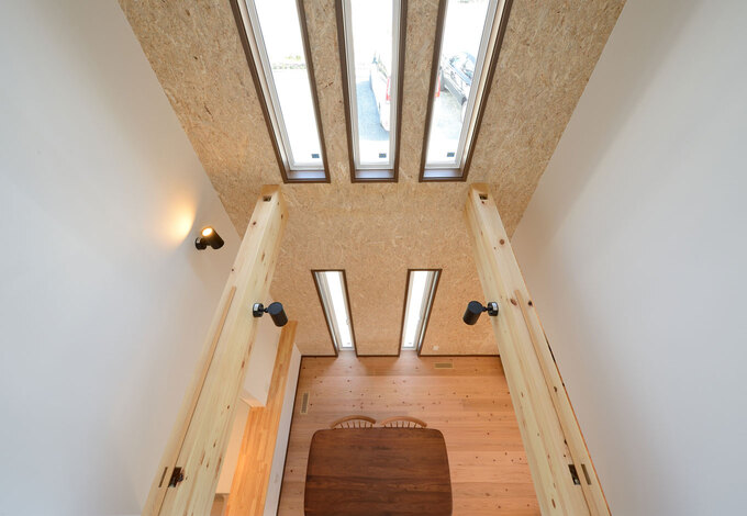 2階ホールからダイニングを見下ろす。1階の床から天井に届くまで強度の強いOSB合板を贅沢に使用。塗り壁よりもリーズナブルで、メンテナンスもラクラク。飾り棚を取り付けるなど、自分スタイルで自由に楽しめるのもいい