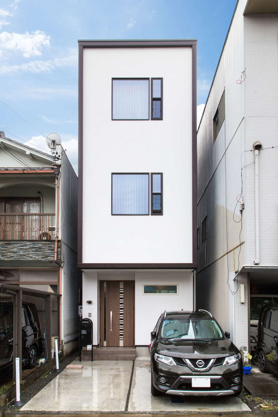 建築システム（狭小住宅専門店）【収納力、狭小住宅、鉄骨鉄筋コンクリート構造】モダンな雰囲気のデザインの窓と白い壁、ダークブラウンのトリミングがおしゃれな外観。間口はわずか3.6m、奥に延びる敷地は典型的な「うなぎの寝床」だ