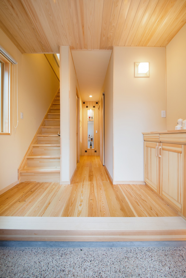 瀧口建設｜洗い出しの土間と珪藻土の壁、無垢の床と天井が美しく調和した、端正な玄関。玄関収納とオープンラックを設け、靴やアウトドア用品などをすっきりとしまい込める