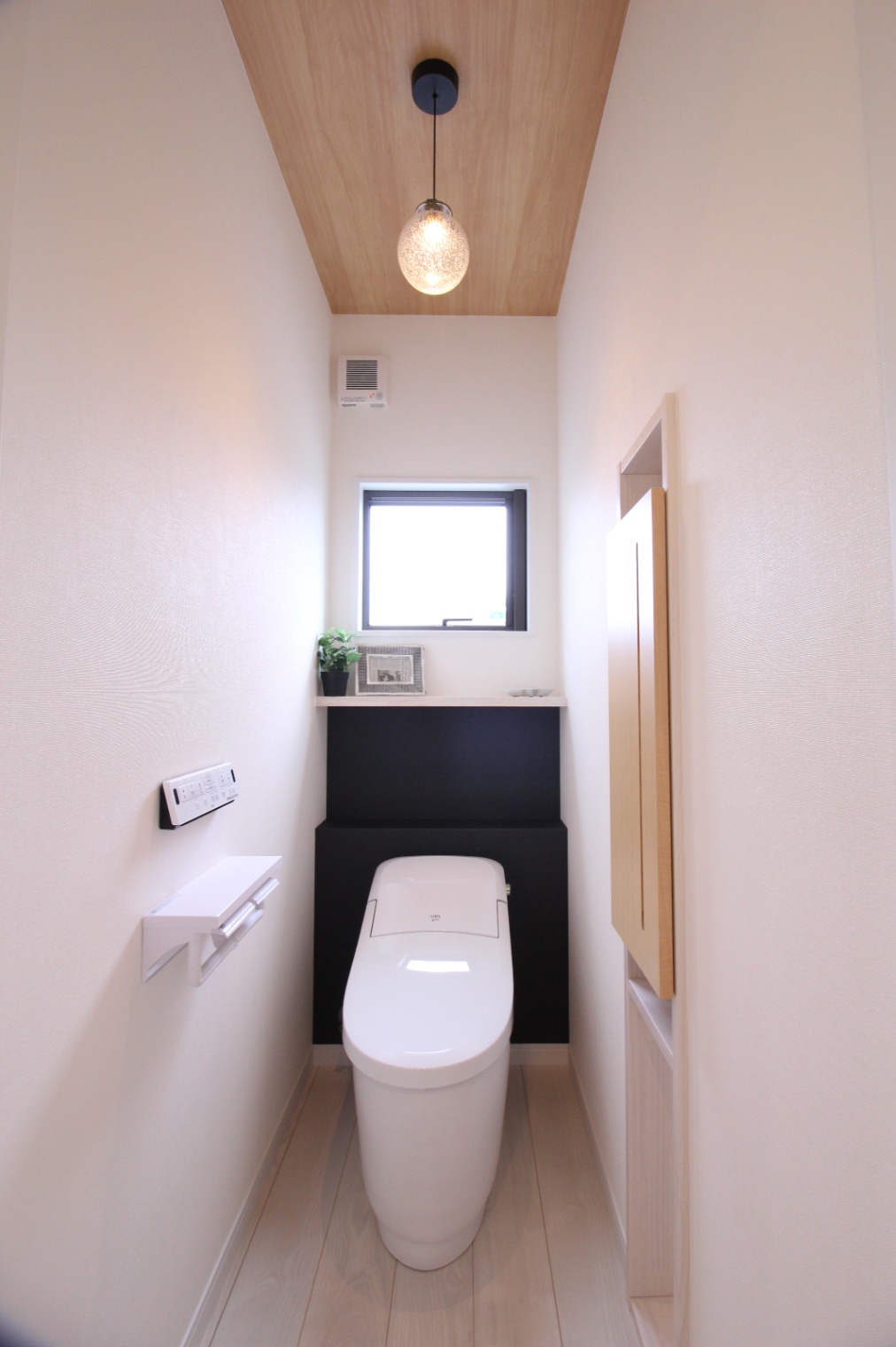 小野田産業～designers house project～｜シンプルでモダンなデザインのトイレ。天井の木目が温かみを加え、ペンダントライトが空間をおしゃれに演出している。
