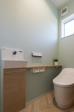 清潔感溢れるトイレは、ペールグリーンの壁が優しい印象を与える。コンパクトな手洗いスペースも完備