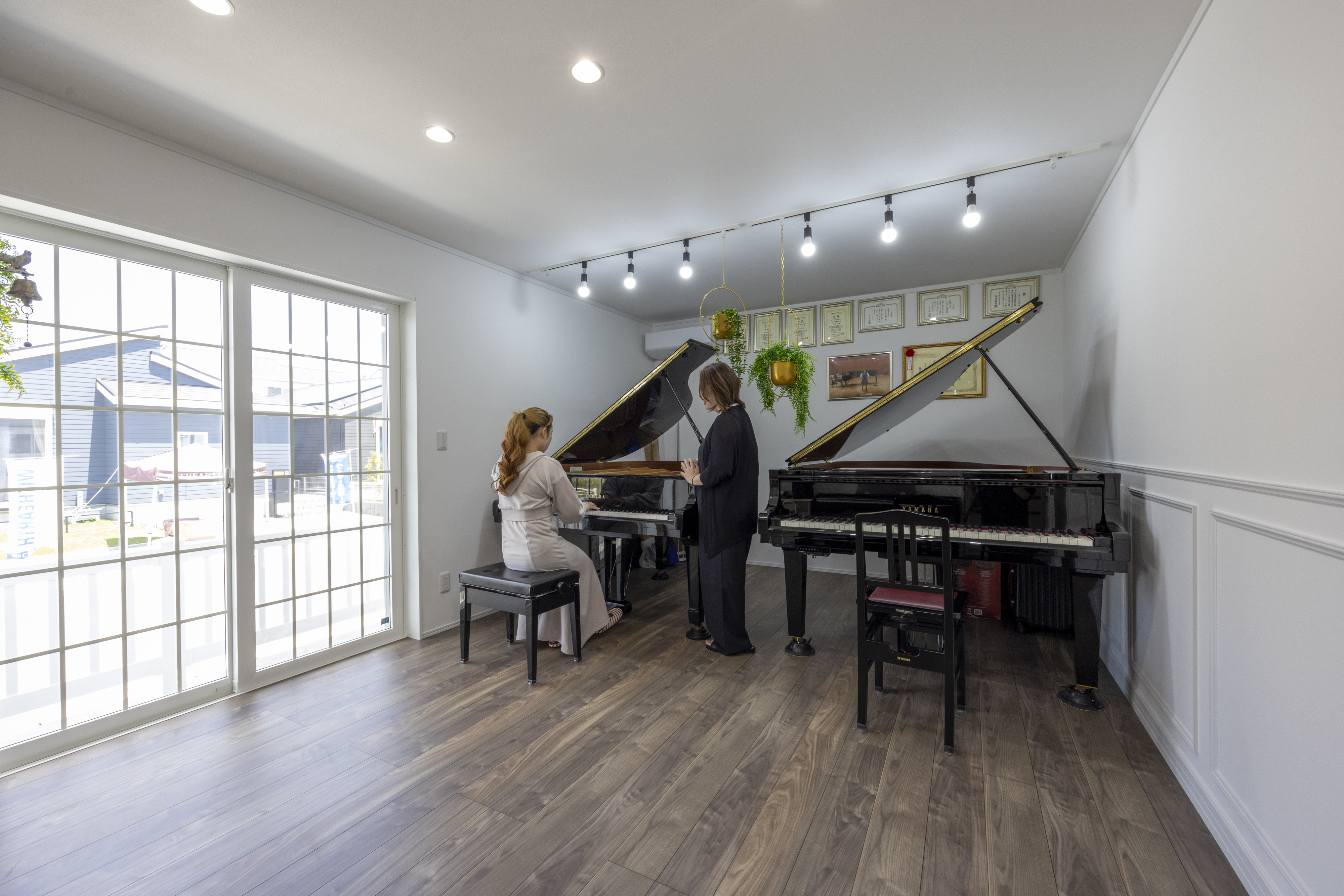 広島建設 セナリオハウス｜自然光が差し込む明るい音楽ルームに、グランドピアノが並ぶ。音響を考慮した設計で、演奏と練習に最適な環境が整っています。