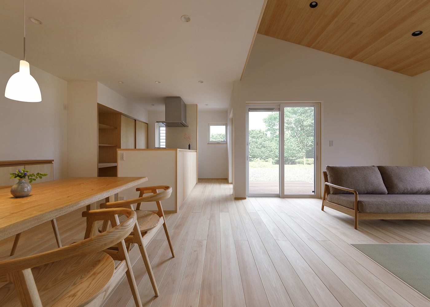 灯建築舎【デザイン住宅、和風、自然素材】開放的でありながら、素材の質感や目にはいる景色がしっとりとした落ち着きを感じさせてくれるLDK。床のヒノキは節のない上質なもの。壁は調湿・消臭効果をもつ珪藻土が採用され、健やかな住環境が提供される。窓の外にはウッドデッキ、その先に庭が続き、目にもうれしい眺めが届く