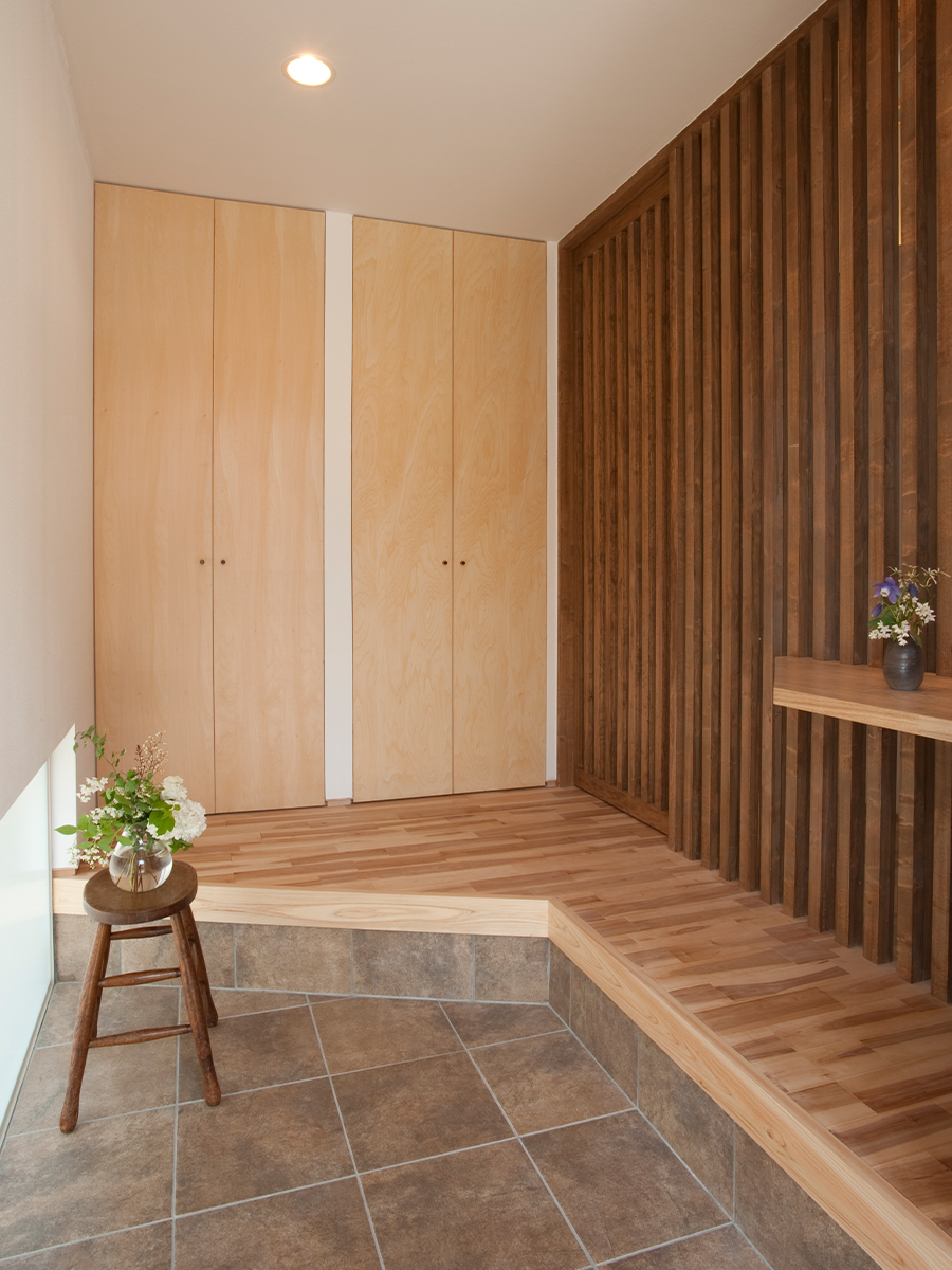 斉藤工務店｜木を基調にした温かみのある玄関ホール。花が飾られ、訪れる人を心地よく迎える雰囲気が感じられる。