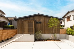木材を使用したナチュラルな外観の平屋。シンプルながら自然と調和したデザインで、コンクリートの敷地がモダンな印象を与えます。