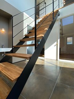 シックなデザインのスケルトン階段。開放感あふれる空間を演出し、モダンなインテリアに溶け込んでいる。木の温かみとメタルのクールさが融合したスタイリッシュな印象。