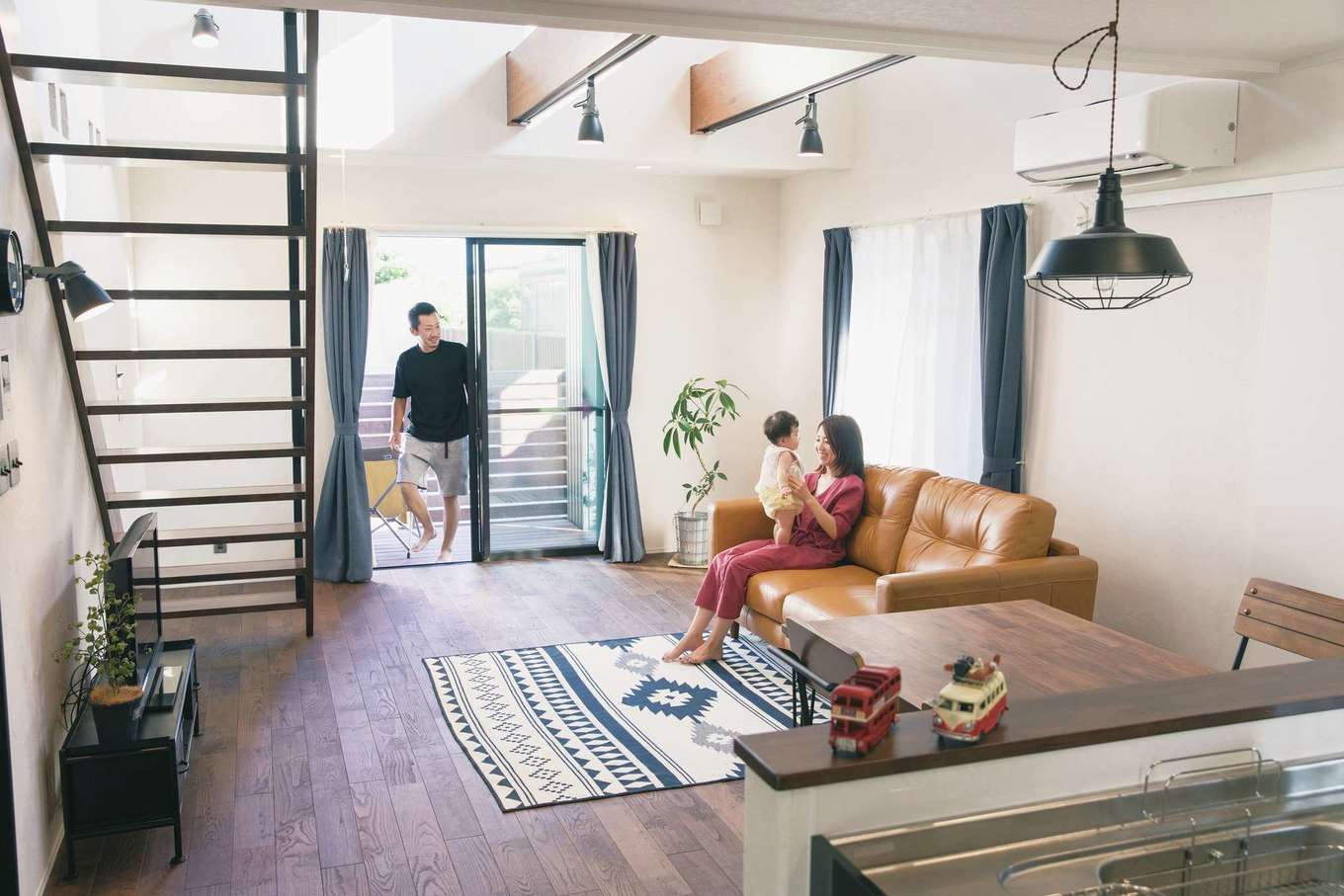 Yamaguchi Design 【デザイン住宅、趣味、インテリア】ウッドデッキと繋がるLDKは、大きな吹抜けとストリップ階段で開放感がいっぱい。無垢とアイアンを用い、室内にいながらにしてアウトドア気分を味わえる雰囲気を演出