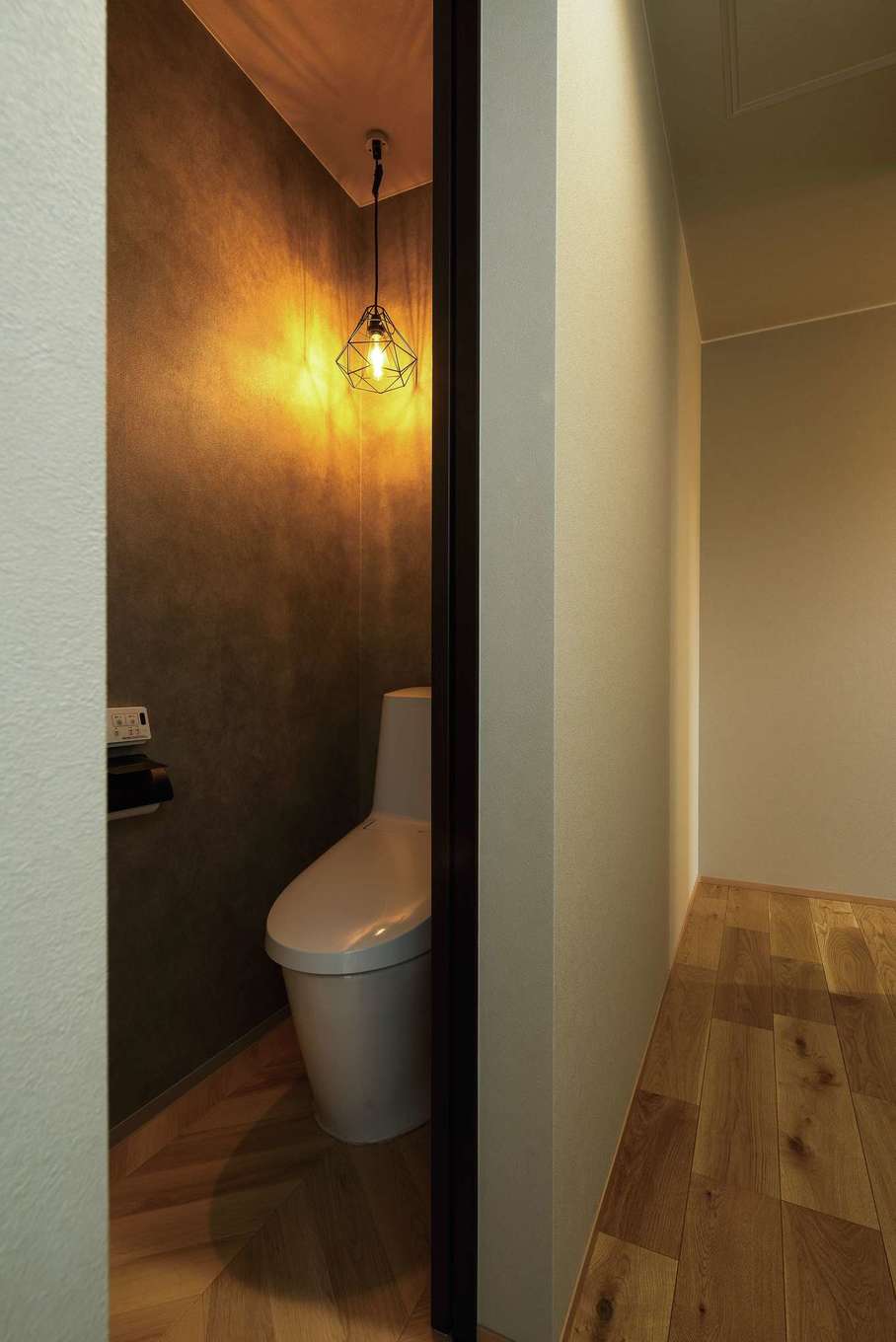 HAPPY HOUSE（山田工務店）【デザイン住宅、省エネ、インテリア】トイレは濃いグレーのクロスと暖かな照明で、ほっと落ち着く空間に。ニッチのペーパー置き場が用意されている