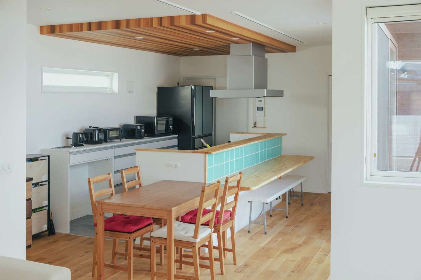 内田建設【デザイン住宅、建築家、平屋】家事効率を高めてくれるアイランド型のキッチン。水色の名古屋モザイクのタイルがアクセントに。下がり天井はレッドシダー調のクロスで、高級感が生まれた