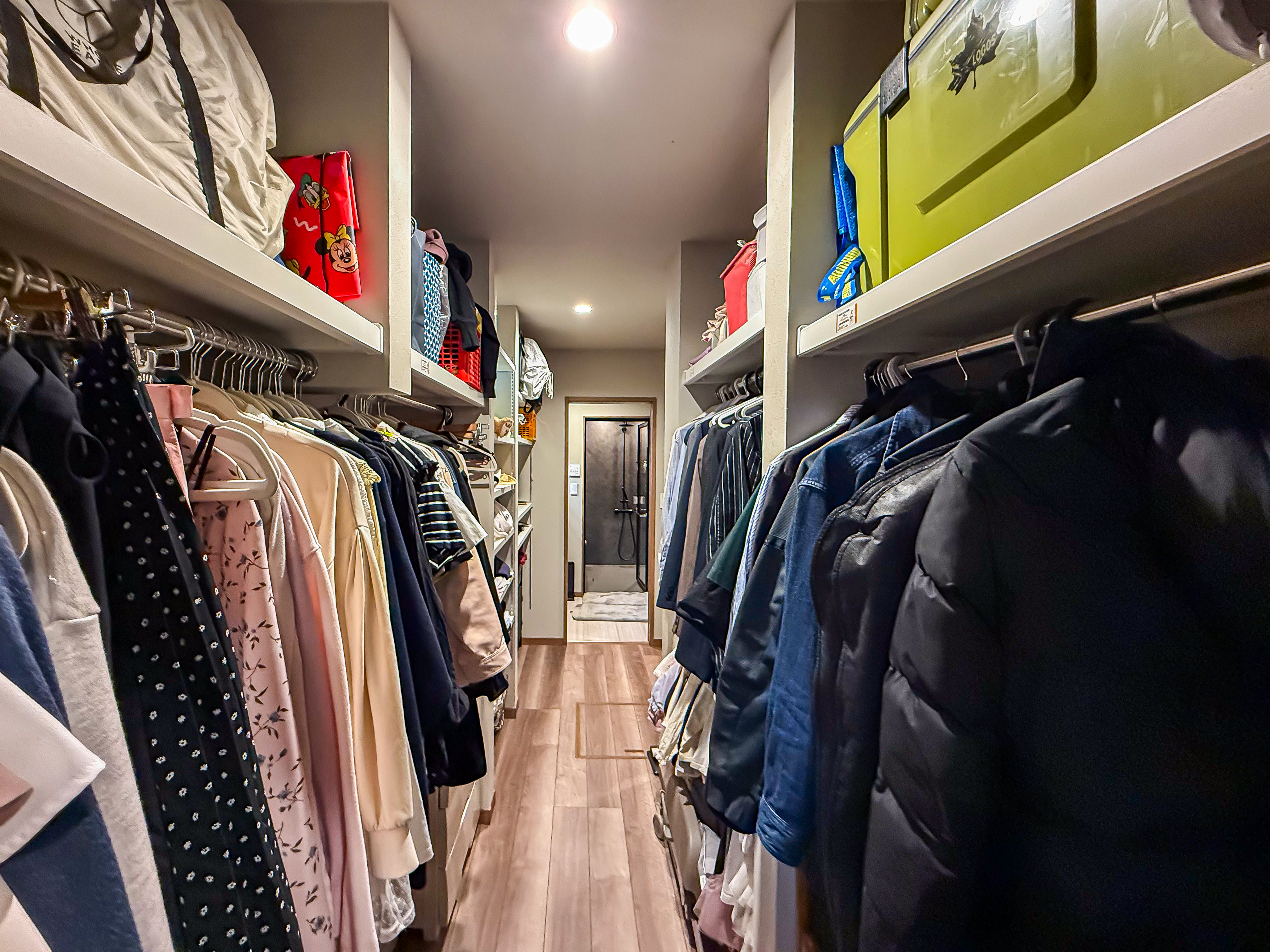 ロイヤルウッド｜両側に収納が設置されたウォークインクローゼット。多数の衣類が整然と並び、アクセスしやすいレイアウトとなっている。