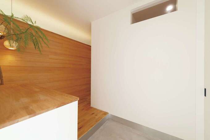 スタイリッシュな土間仕立ての玄関。壁上部の間接照明がやわらかく迎えてくれる