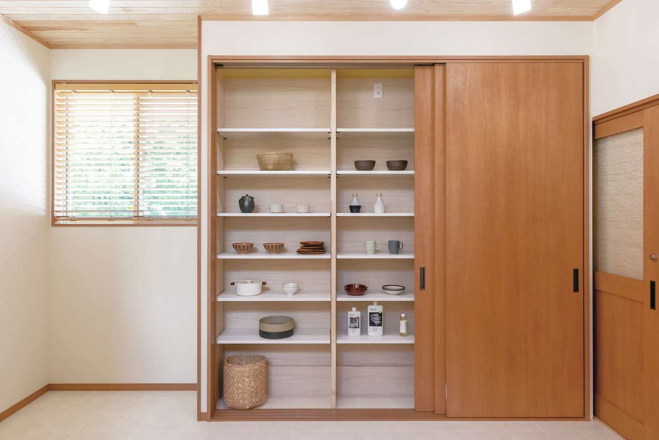住まいるコーポレーション【デザイン住宅、自然素材、平屋】キッチンの背面の造作収納は、大きな扉で隠してしまえるようになっていて、生活感を隠してＬＤＫをオシャレに演出できる。器や食品などもたっぷりしまえて便利