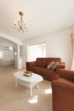 暖かい色調のソファとシャンデリアが演出するリビング。ホワイトのカーテンがシンプルな美しさを引き立てている。