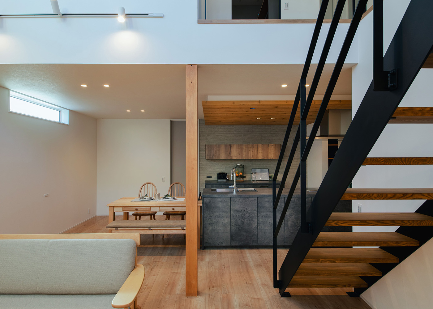DAITOKU（大得工務店）【デザイン住宅、省エネ、間取り】キッチンで作業していても、吹抜けを通して2階の気配を感じとることができるので安心。鉄骨のスケルトン階段が開放感を生み出すと同時に、インテリアのアクセントにもなっている