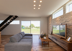 白と木目を基調としたリビング。テレビステーションには材質の異なるゴツゴツとした風合いがおもしろいタイルを使用し、表情をつけた。壁の上部に窓を設け、リビングに柔らかな光が降り注ぐようにプランニング。大きくとった掃き出し窓で公園の緑を借景に。隣の広い公園が自宅の庭の延長線上にあるかのように感じられる眺め