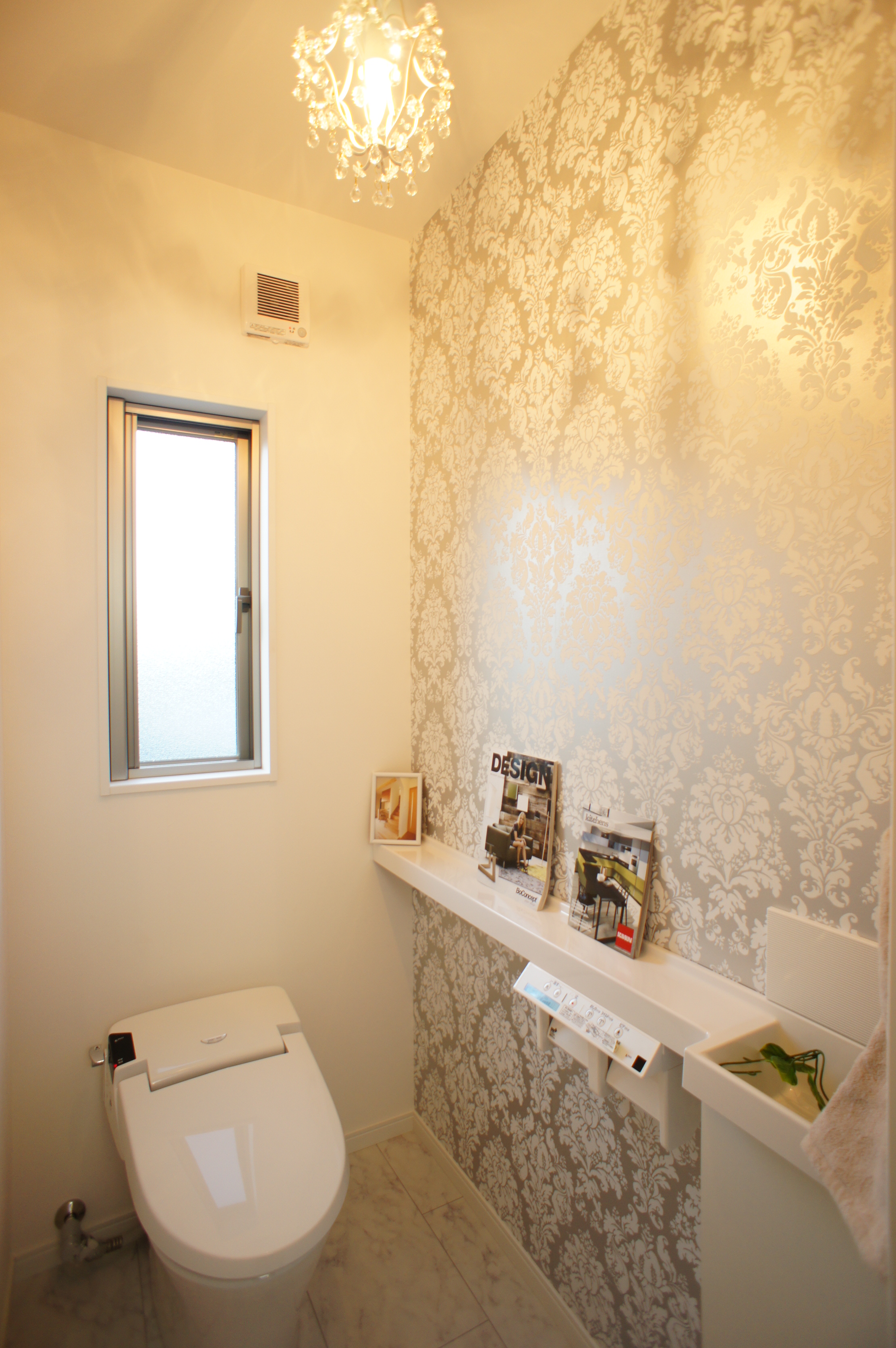 小野田産業～designers house project～｜エレガントな壁紙が印象的なトイレ。窓からは自然光が入り、明るい雰囲気を演出している。